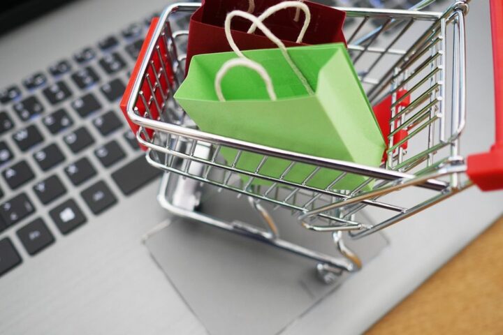 Miniature shopping trolley with bags on a laptop keyboard