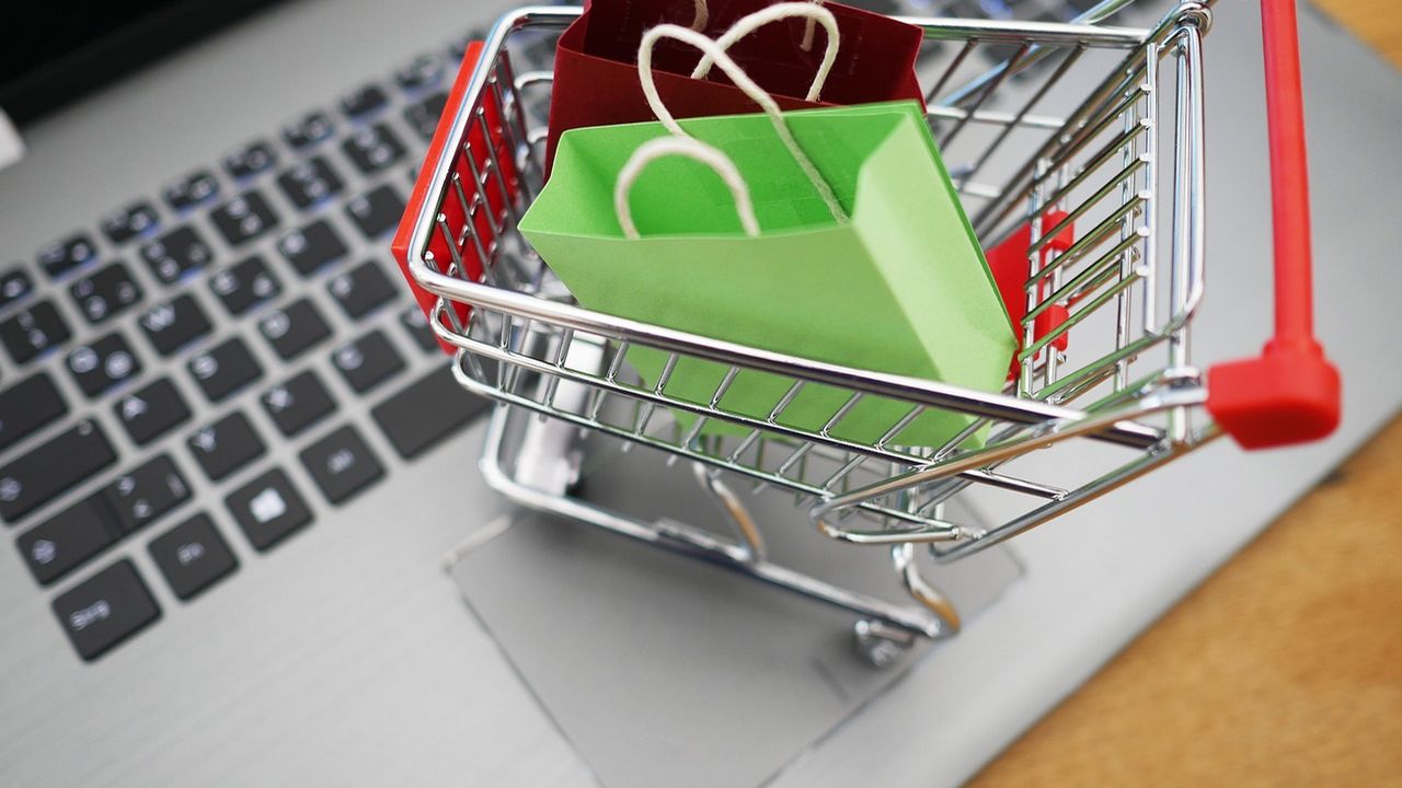 Miniature shopping trolley with bags on a laptop keyboard