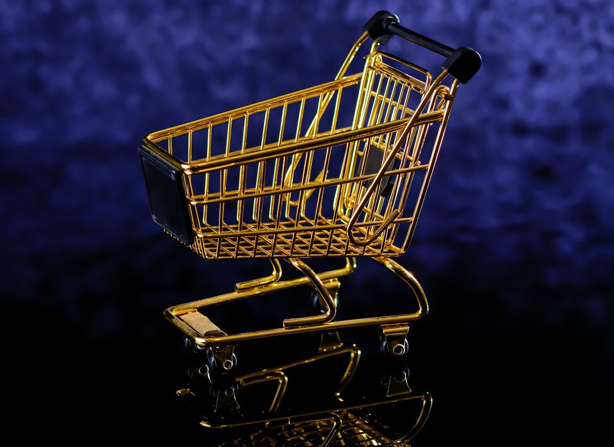 Gold shopping trolley against a dark blue background