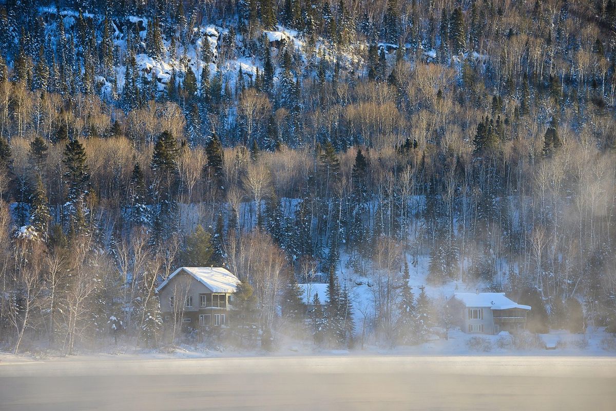Aerial view of a frosted forest with a cabin