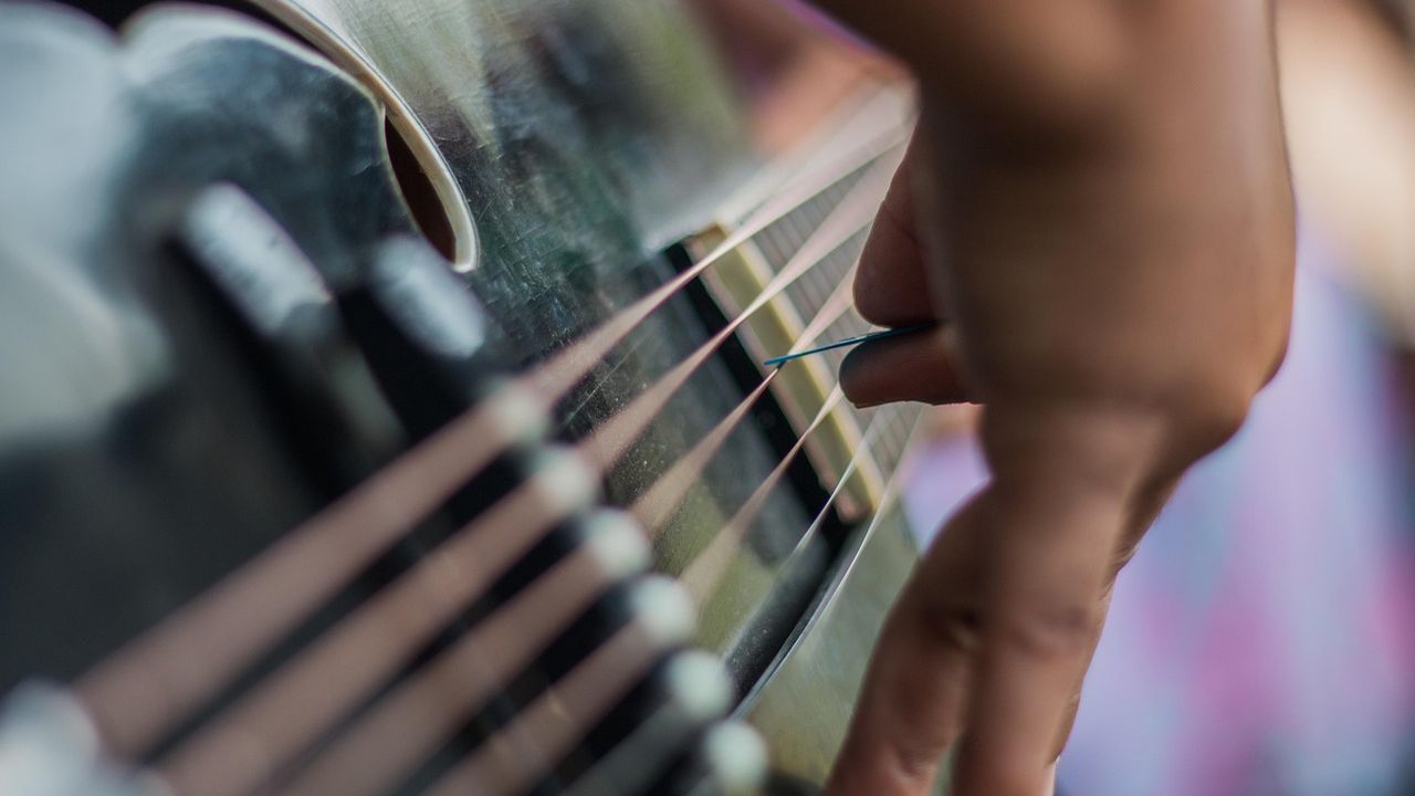 Close-up of fingers plucking guitar strings