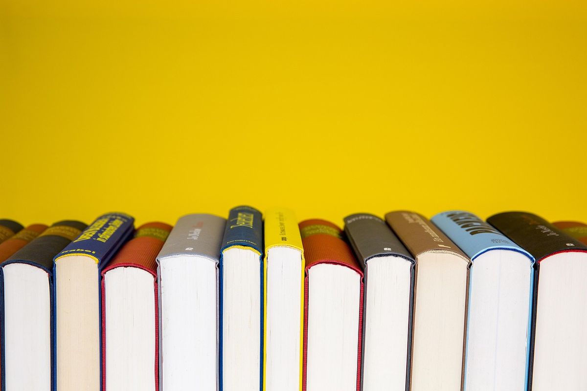 Row of hardback books against a yellow wall