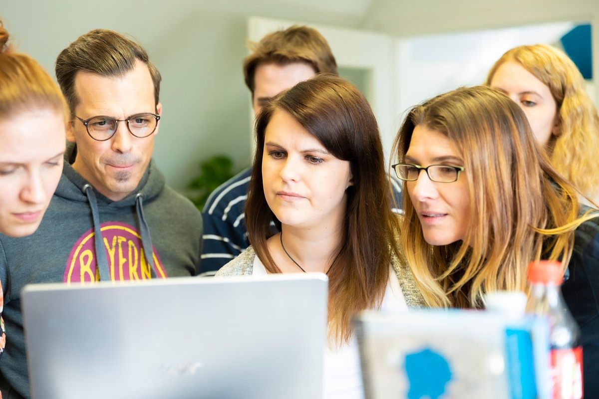 Colleagues gathered around a laptop learning together