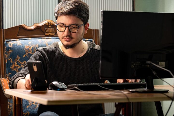 Young man working at a computer at a wooden desk