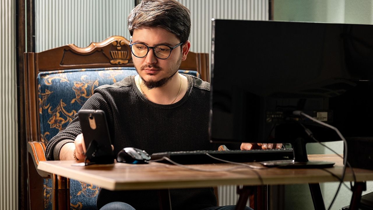 Young man working at a computer at a wooden desk