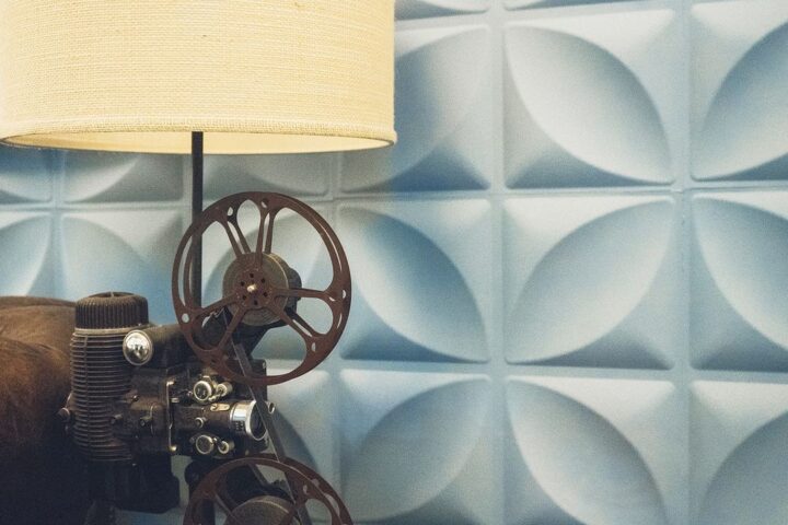 Vintage film projector beside a lamp against a patterned wall