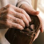 Elderly hands taking coins from a worn leather purse