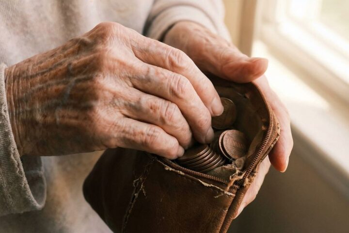 Elderly hands taking coins from a worn leather purse
