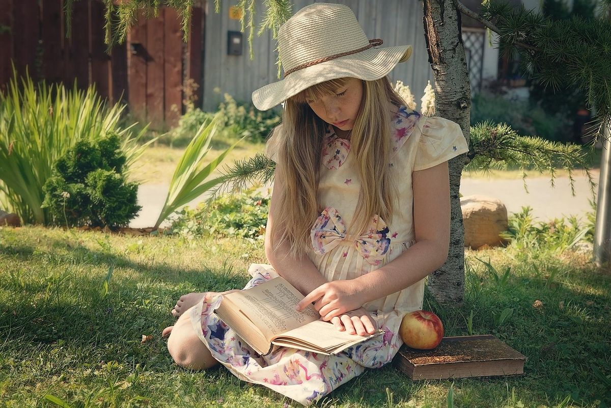 Girl in a sun hat reading in the garden