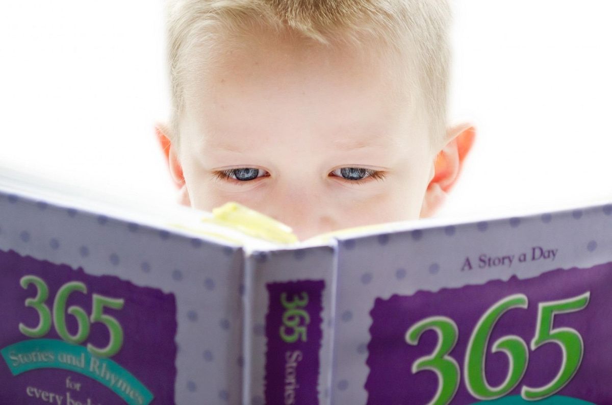 Young child peering over a book