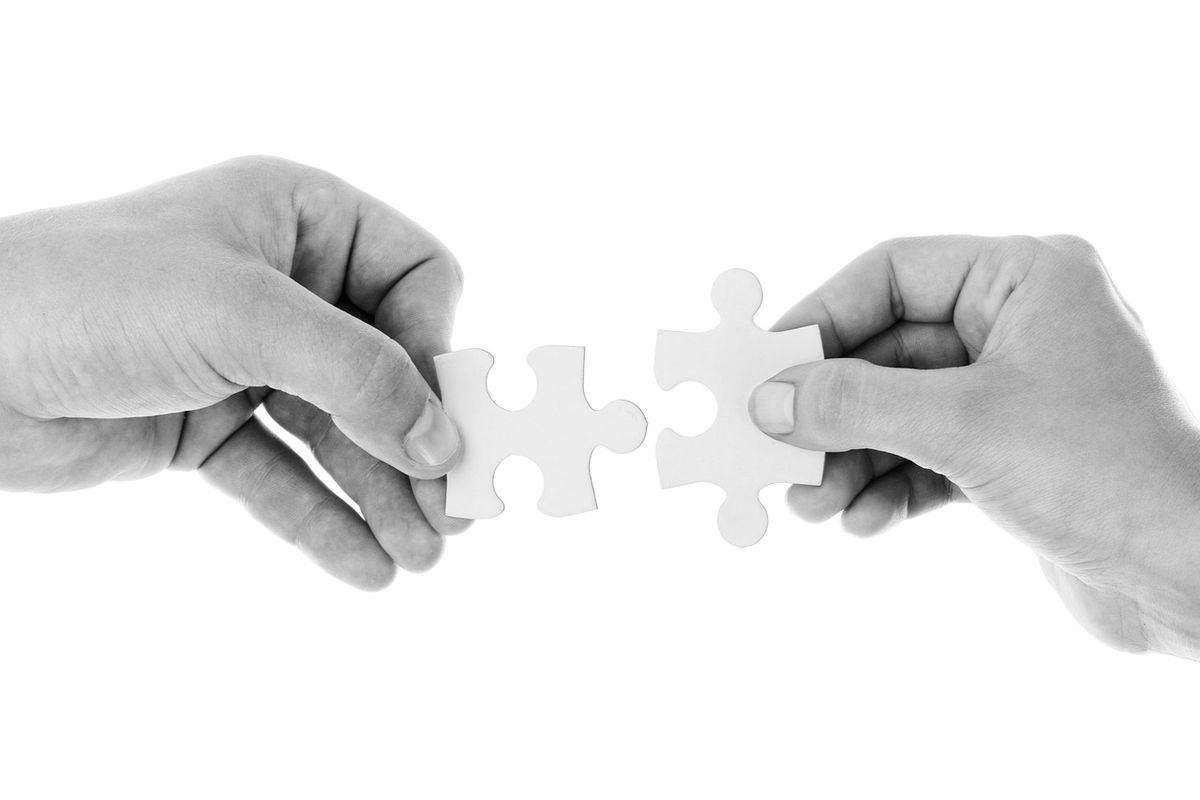 Two hands fitting jigsaw pieces together