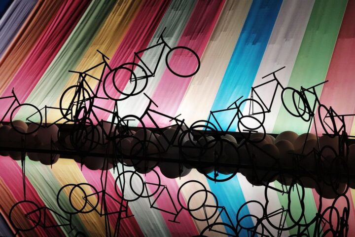 Bicycle sculptures in front of a wall of rainbow-coloured fabric strips