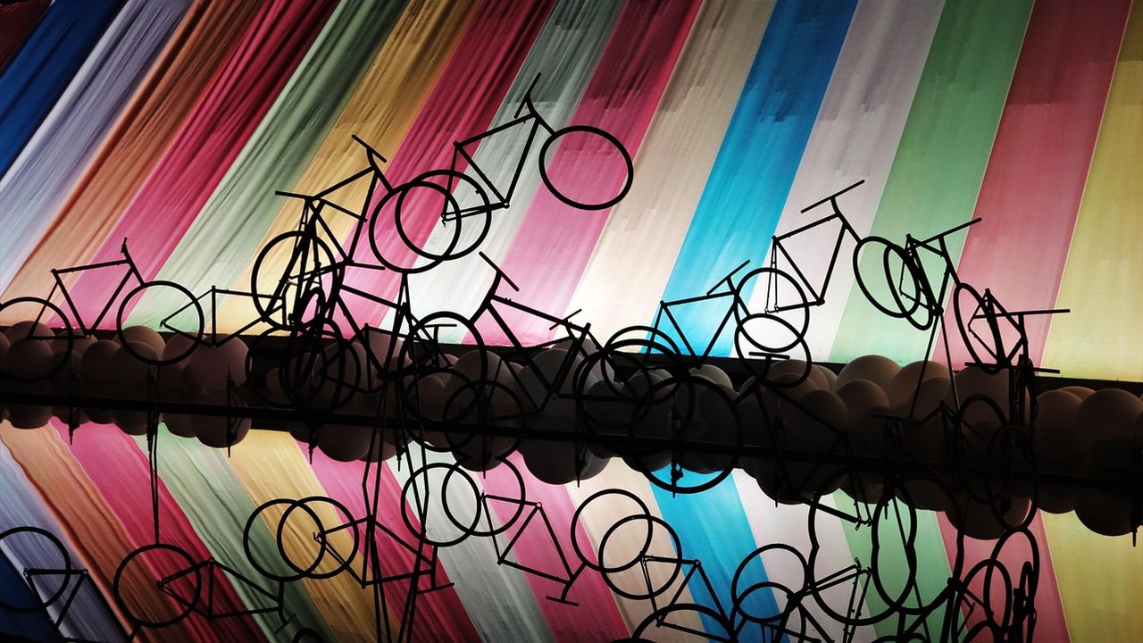 Bicycle sculptures in front of a wall of rainbow-coloured fabric strips