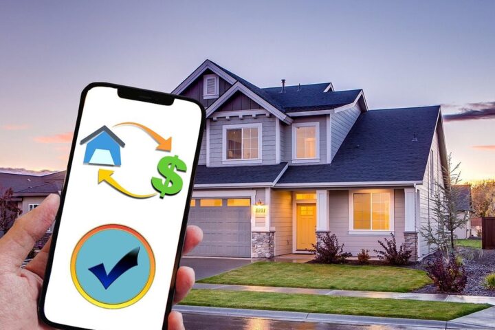 Hand holding a phone with a property finance app in front of a house