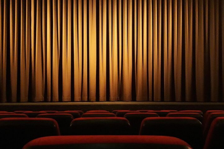 Empty cinema with red seats and a golden curtain