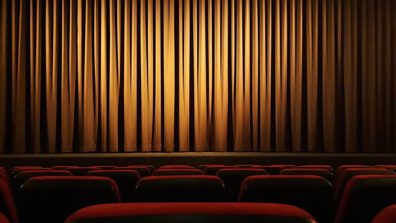 Empty cinema with red seats and a golden curtain