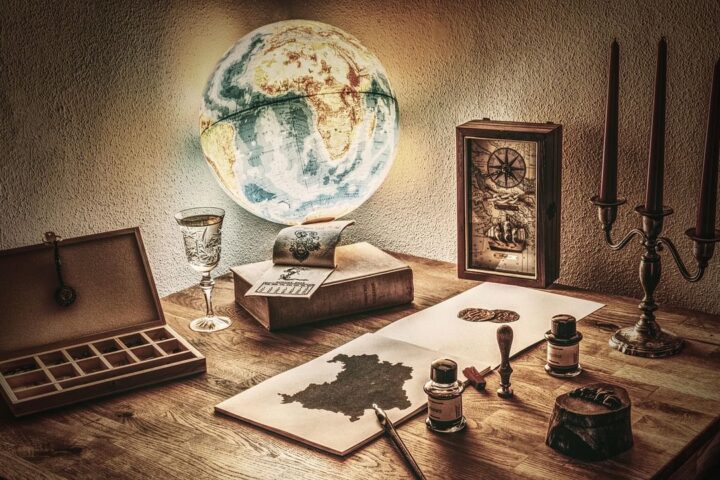Old-fashioned desk with a globe, inkwells, clock and candlesticks