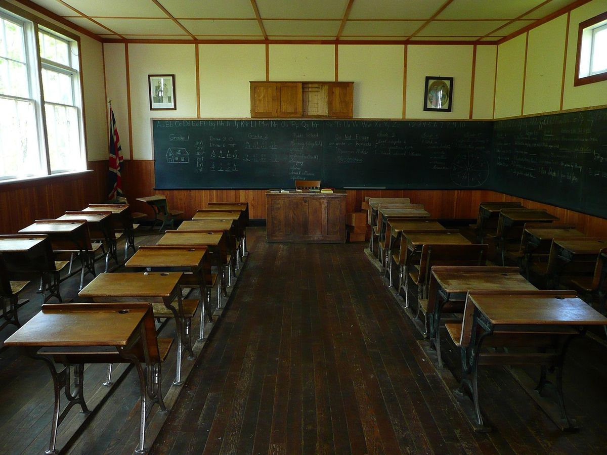 Old-fashioned schoolhouse classroom with wooden desks and a blackboard