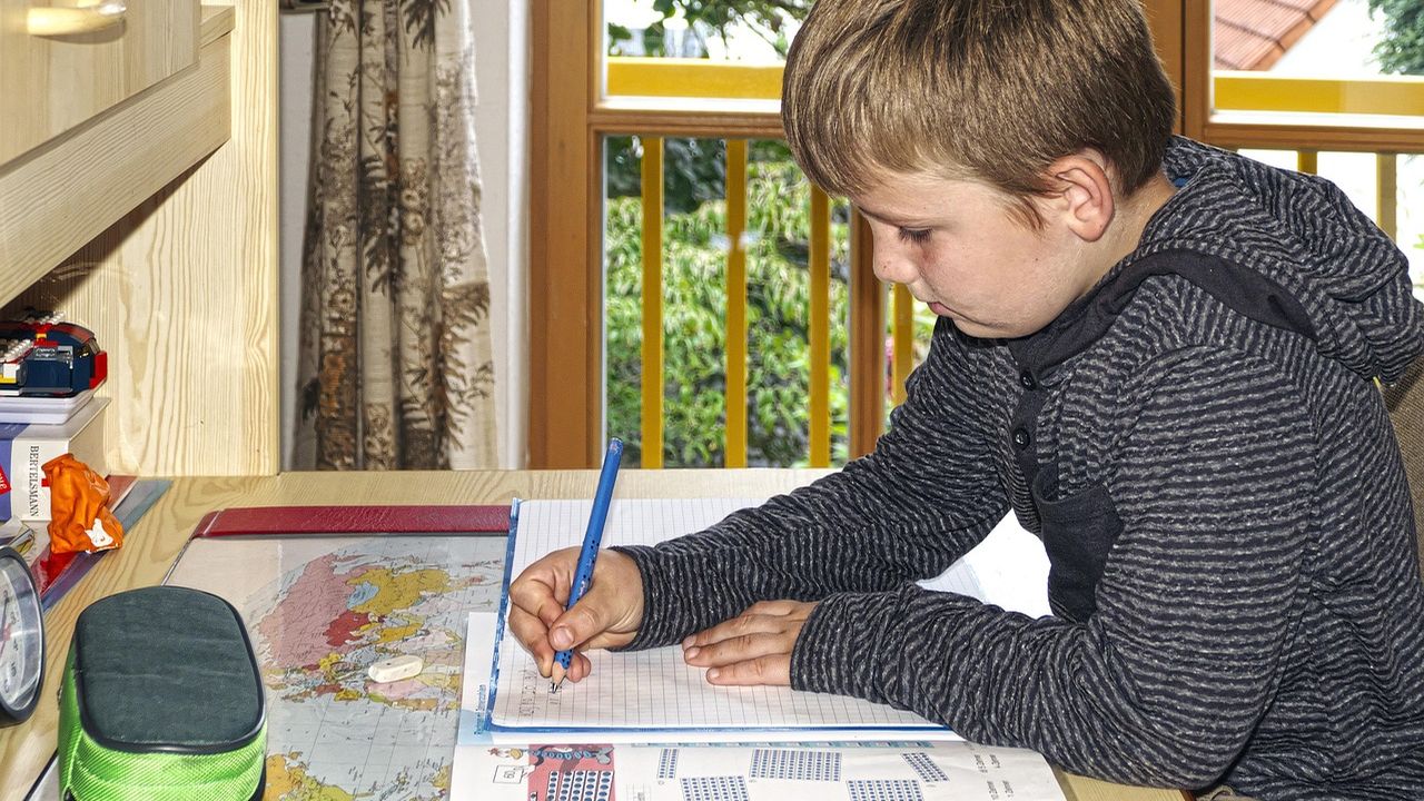 Boy concentrating on writing at a desk
