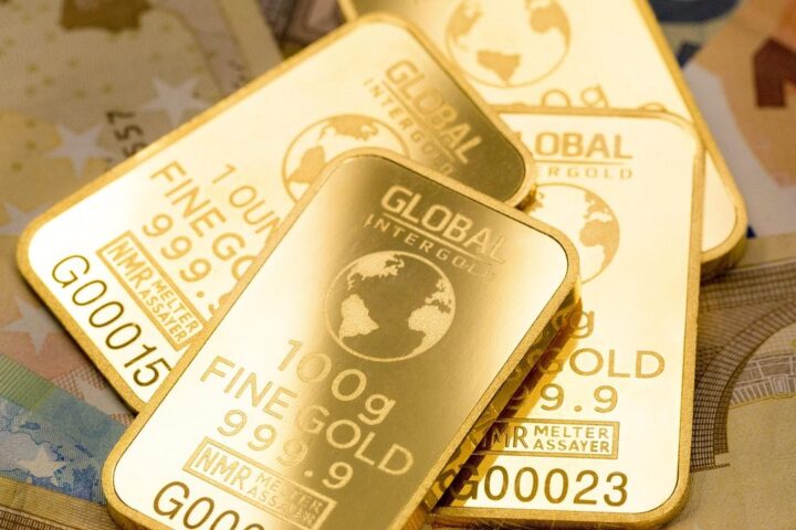 Stack of 100g fine gold bars on banknotes