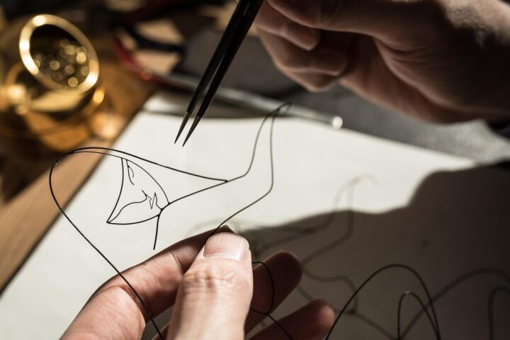 Hands shaping wire with pliers to make jewellery