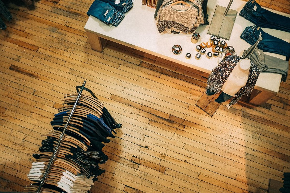 Folded clothes and accessories laid out on a wooden floor