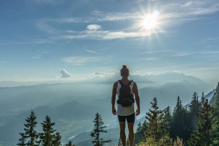 Hiker with a backpack looking out over misty mountains