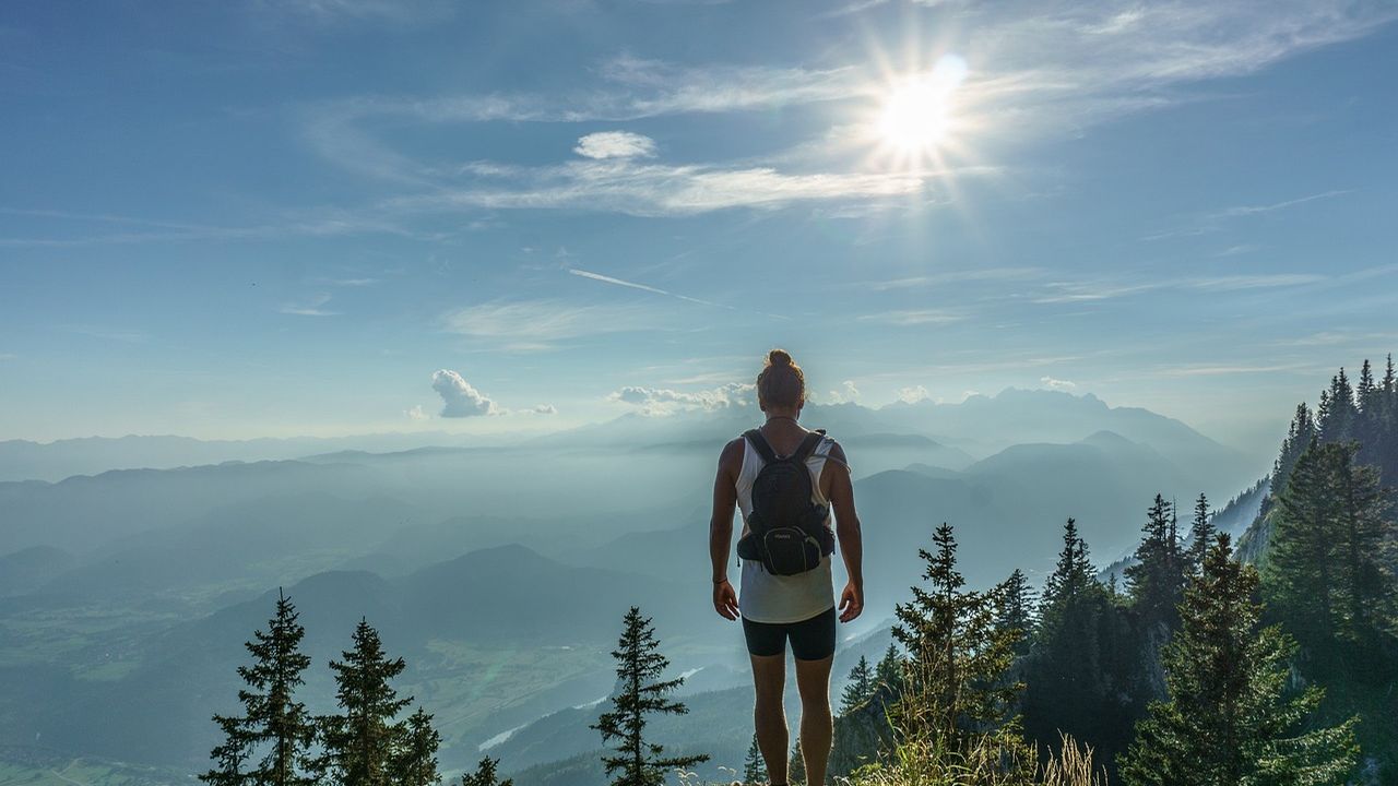 Hiker with a backpack looking out over misty mountains