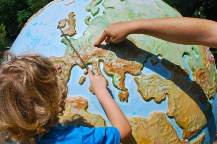 Child and adult pointing at Europe on a large globe