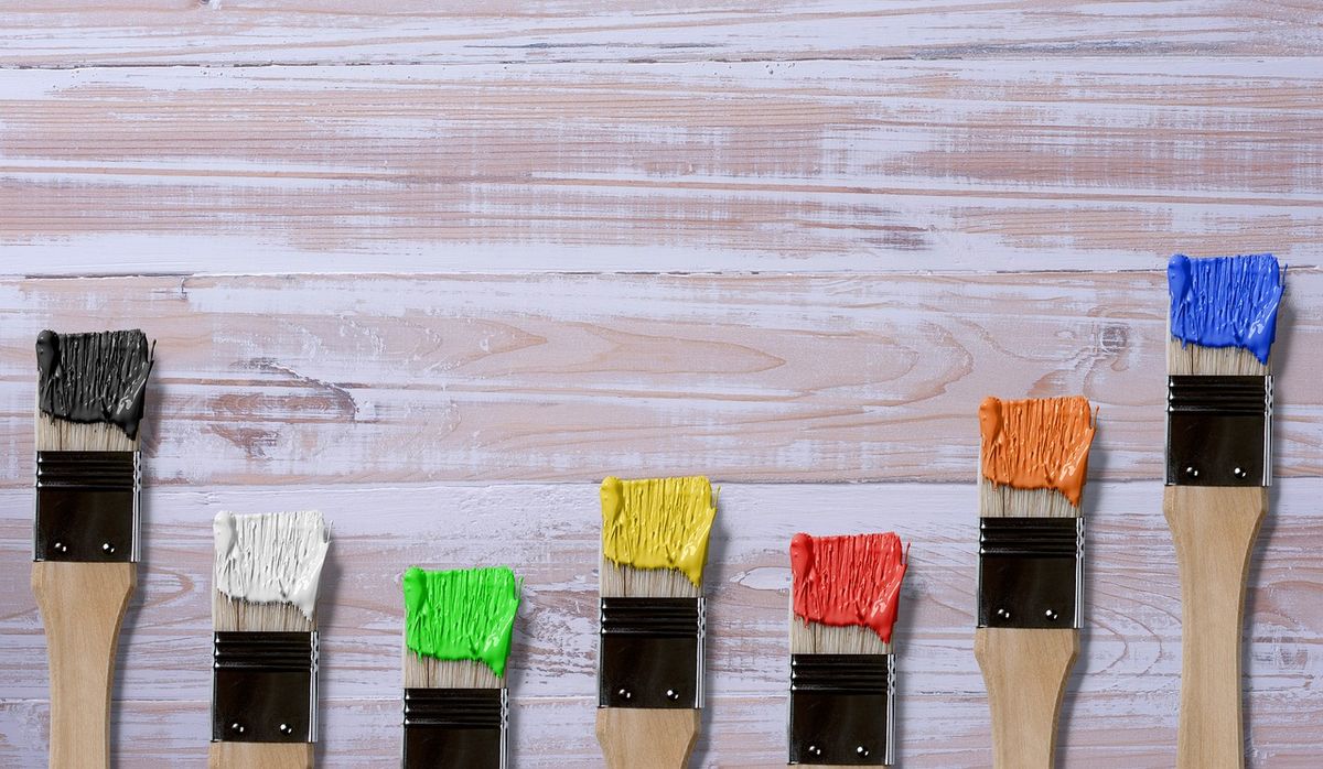 Row of paintbrushes dipped in bright colours on white boards