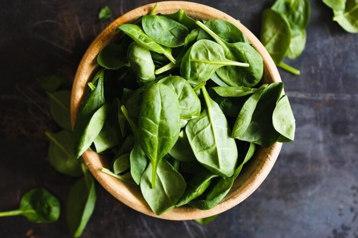 Wooden bowl of fresh spinach leaves