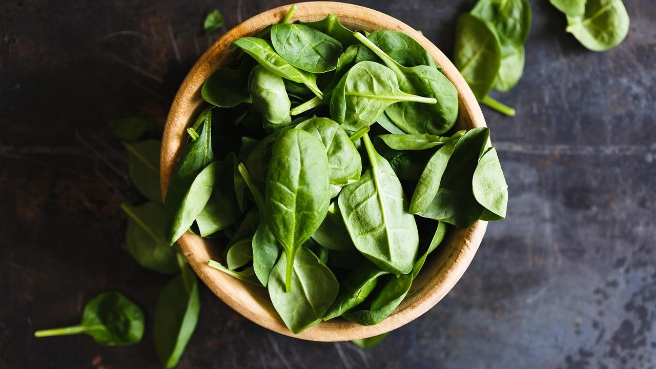Wooden bowl of fresh spinach leaves