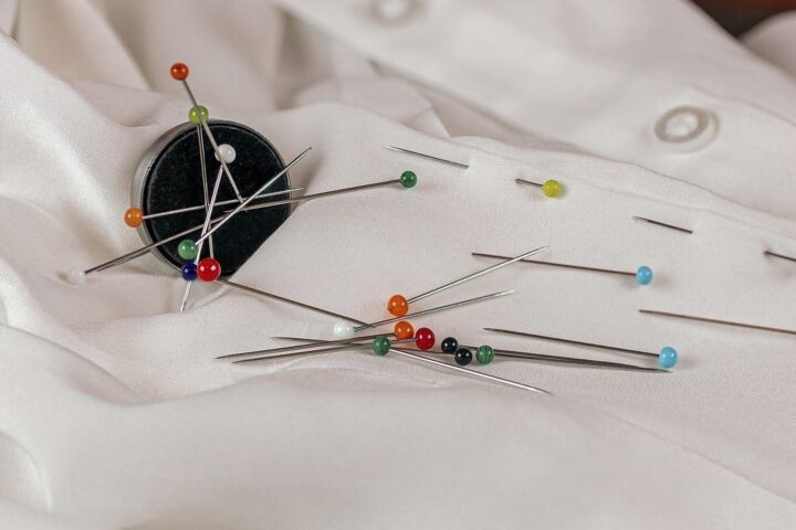 Magnet holding coloured pins on white fabric