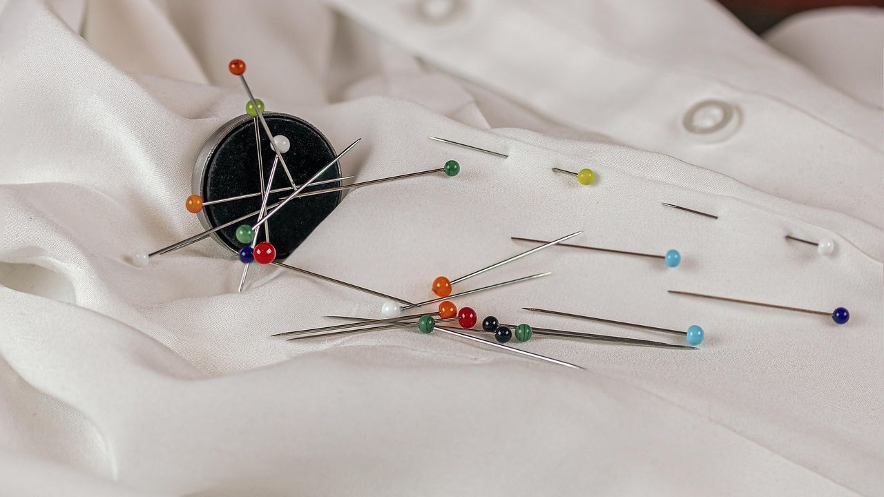Magnet holding coloured pins on white fabric