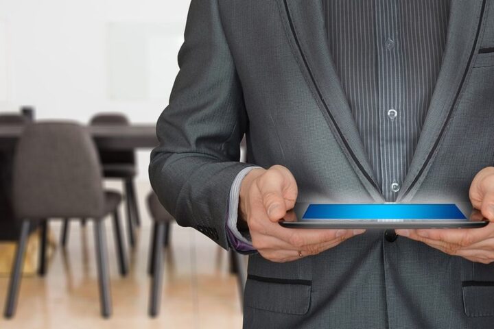 Man in a suit holding a tablet in a meeting room