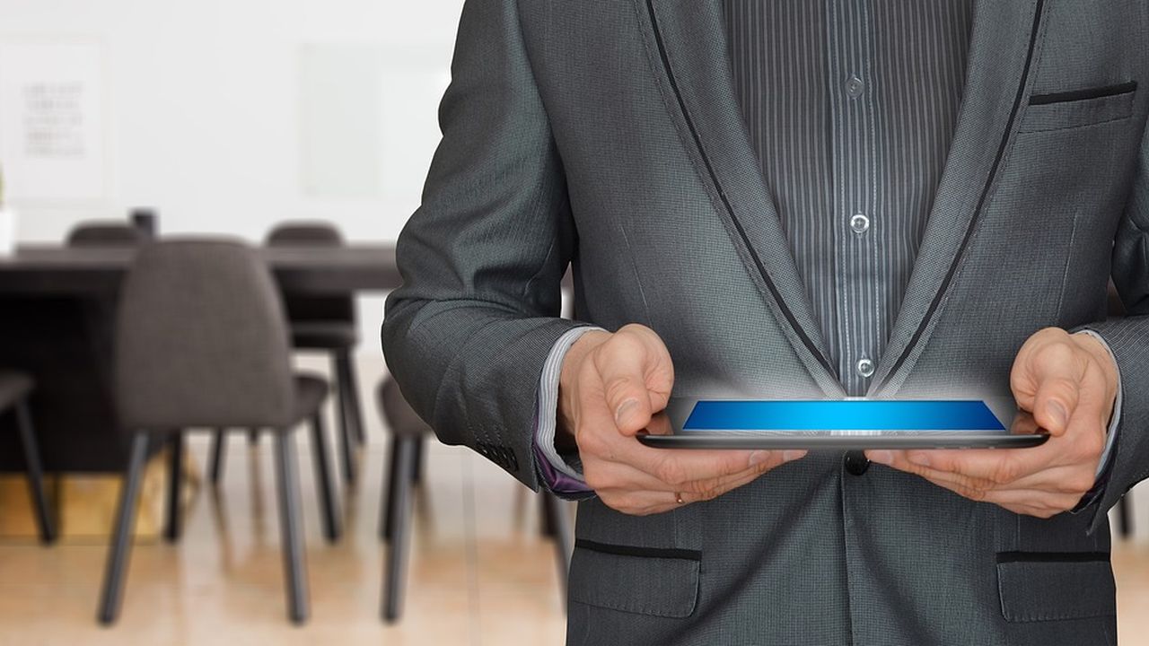 Man in a suit holding a tablet in a meeting room