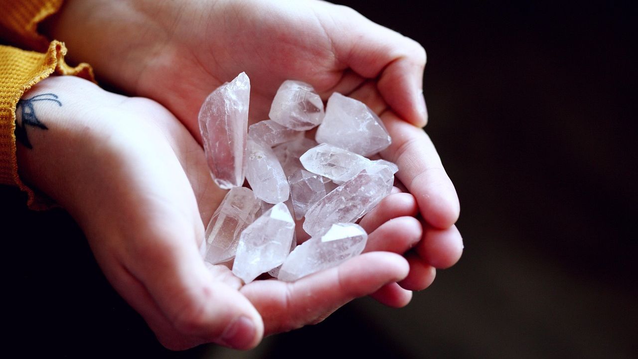 Cupped hands holding clear quartz healing crystals