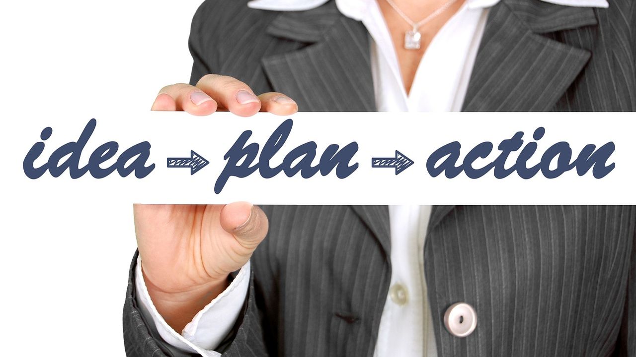 Businesswoman holding a card reading idea, plan, action