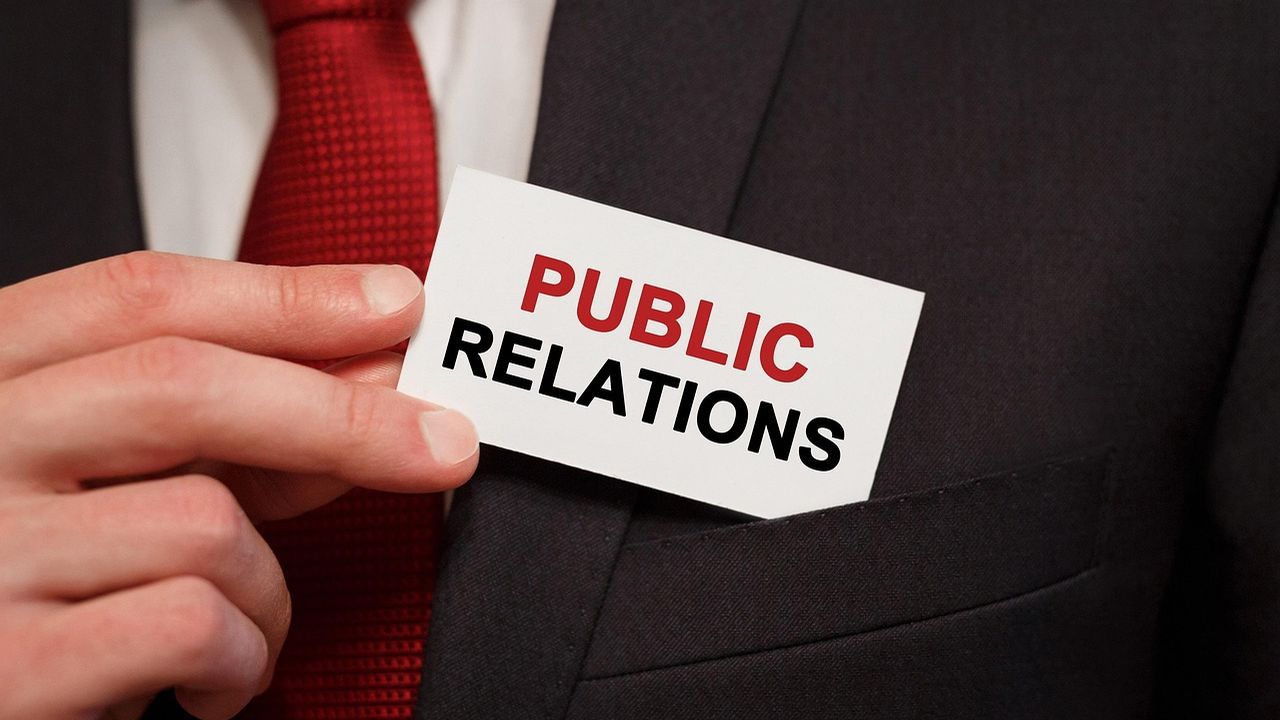 Hand holding a card reading Public Relations