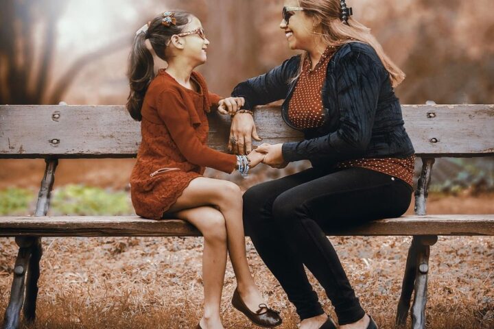 Woman and girl talking on a park bench