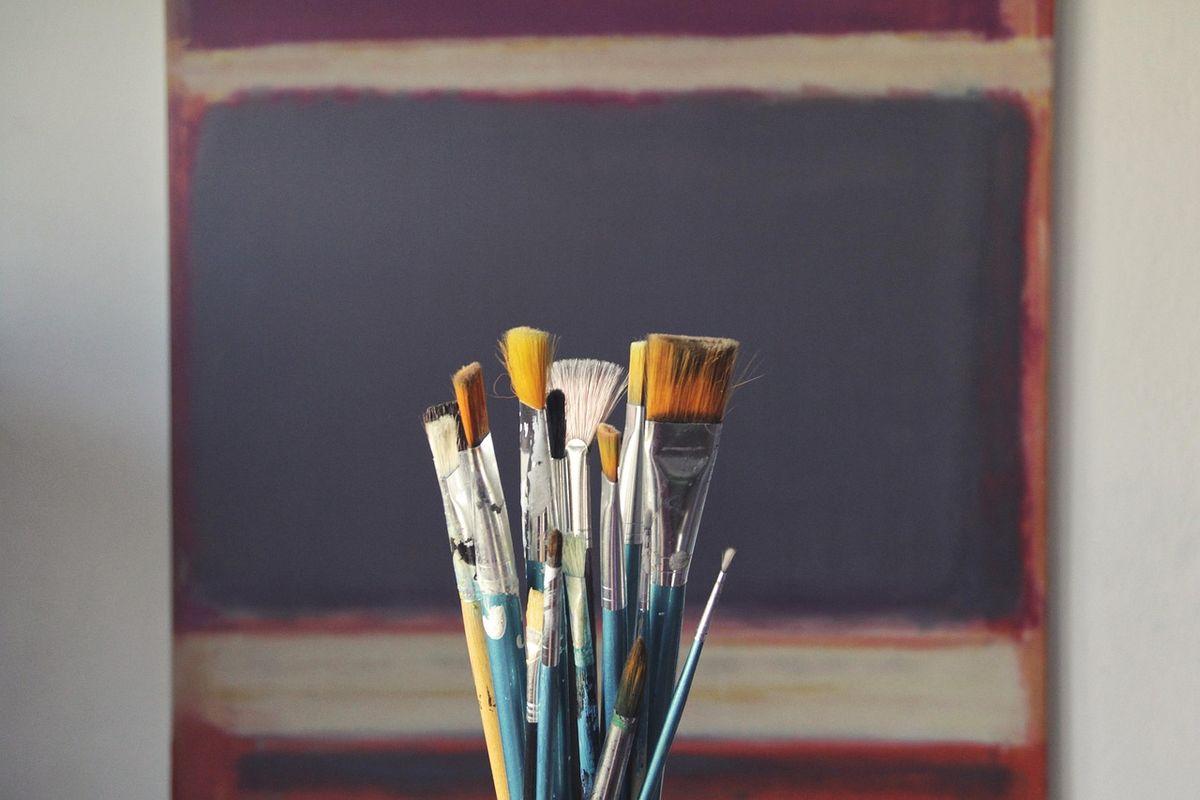 Jar of paintbrushes in front of a chalkboard