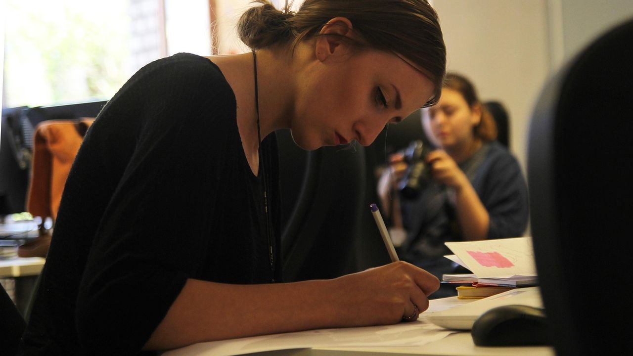 Woman sketching designs at a desk in a creative studio