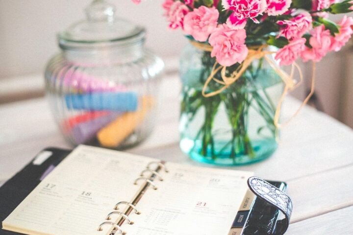 Open planner, pen and flowers on a desk