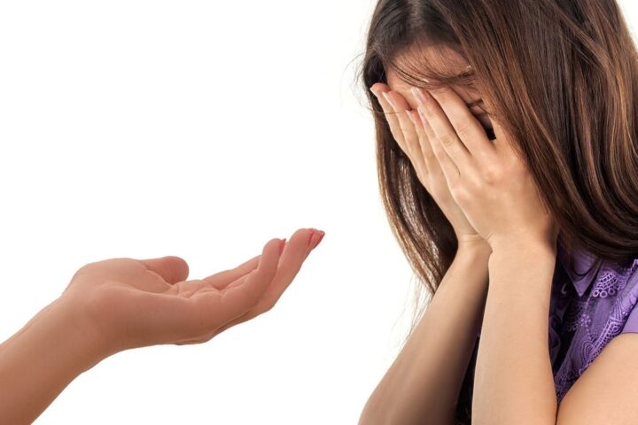 Hand reaching out to a woman with her face in her hands