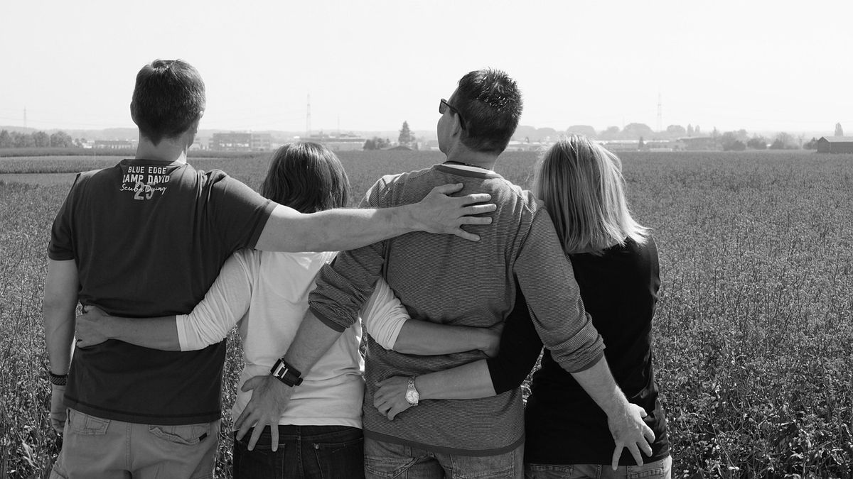 Group of friends with arms around each other in a field