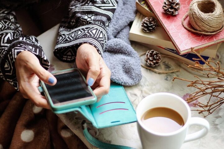 Woman using a smartphone beside a cup of coffee