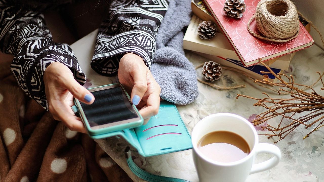 Woman using a smartphone beside a cup of coffee