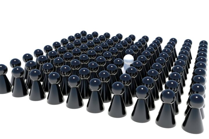 One white game piece standing out among black ones