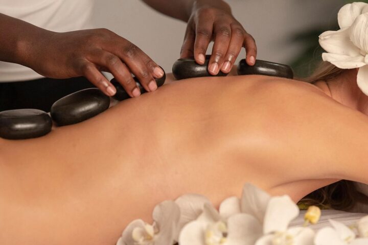Therapist placing hot stones along a woman's back