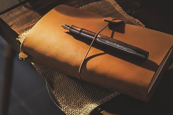 Leather journal and fountain pen on a dark table